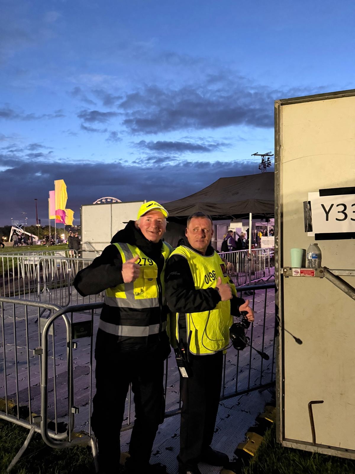 Two PSG UK event staff in hi-vis vests at a festival at night
