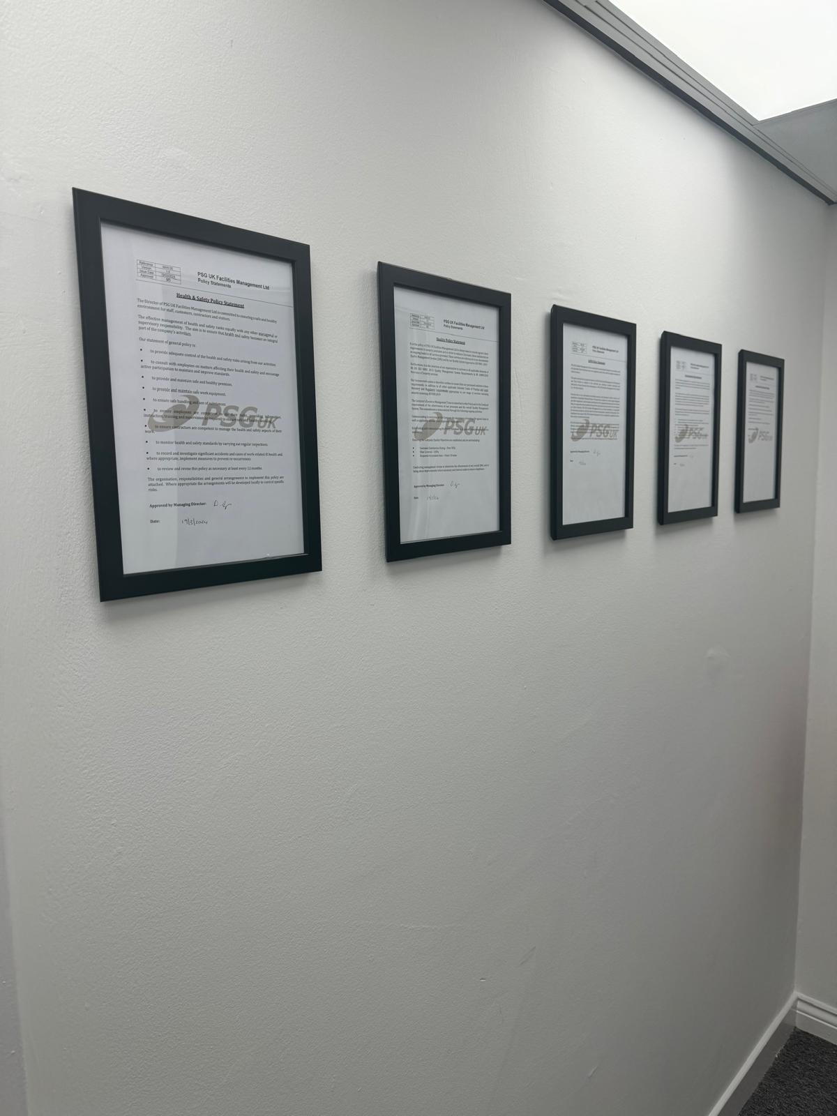 PSG UK framed policy documents displayed on office wall